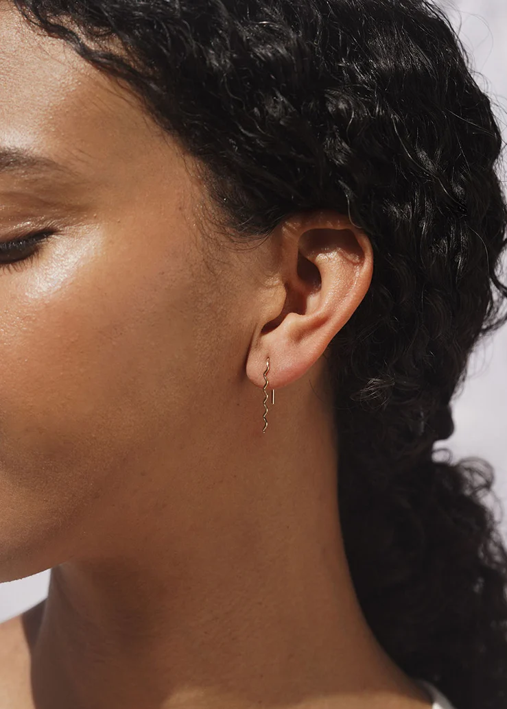Gold wavy earrings shown on a model