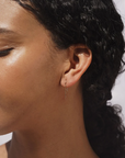Gold wavy earrings shown on a model