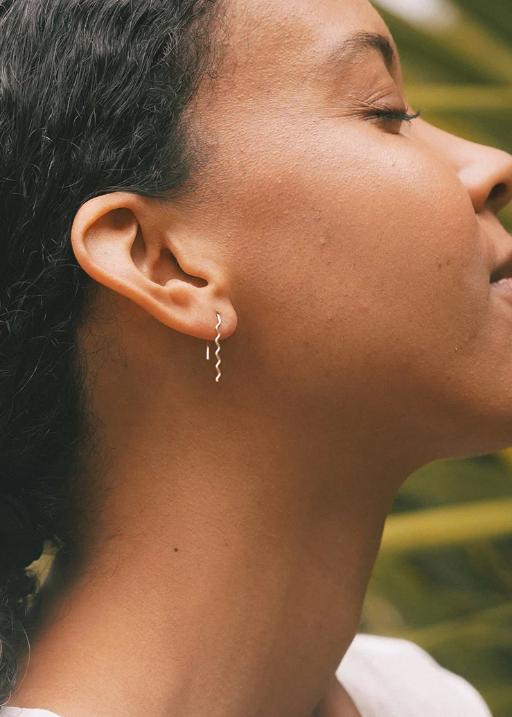 Silver wavy earrings shown on a model