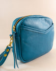 Close-up of cubist handbag in azure, with a v-shaped front pocket and a long thin shoulder strap