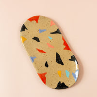 Oval-shaped ceramic tray with funky shapes painted around in various colors from blue to red to pink to black.