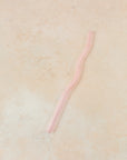 Flatlay of a pink wavy reusable straw.