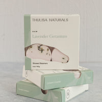 Two boxes of shower steamers with one standing up on top. Boxes are white and green and "lavender geranium" scented