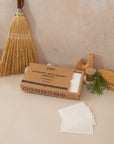 Laundry detergent sheets laid out on a light pink background with earthy props surrounding.