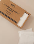 Laundry detergent sheets laid out on a light pink background