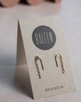 Gold earrings on a BALEEN branded card with a wavy object in the background