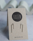 Pair of silver earrings on a 'BALEEN' branded card with a wavy background