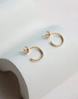 Gold hoop earrings on a light gray surface
