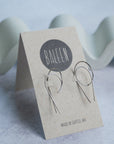 Silver earrings on a 'BALEEN' branded card with a light background