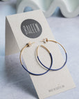 Gold and blue hoop earrings on a 'BALEEN' branded card