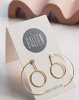 Gold hoop earrings on a BALEEN branded card with a wavy object in the background.