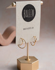 Gold double hoop earring on a stand with 'Baleen' branded card on a neutral background