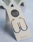 Gold and blue hoop earrings on a Baleen branded card with a light gray background