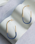 Gold and blue hoop earrings on a light gray surface