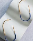 Pair of gold and blue earrings on a textured surface