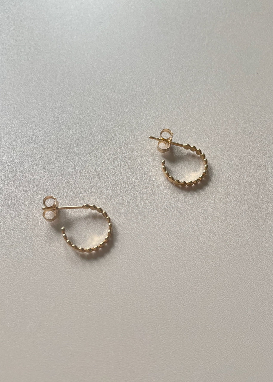 gold hoops as a flay lay on a beige background