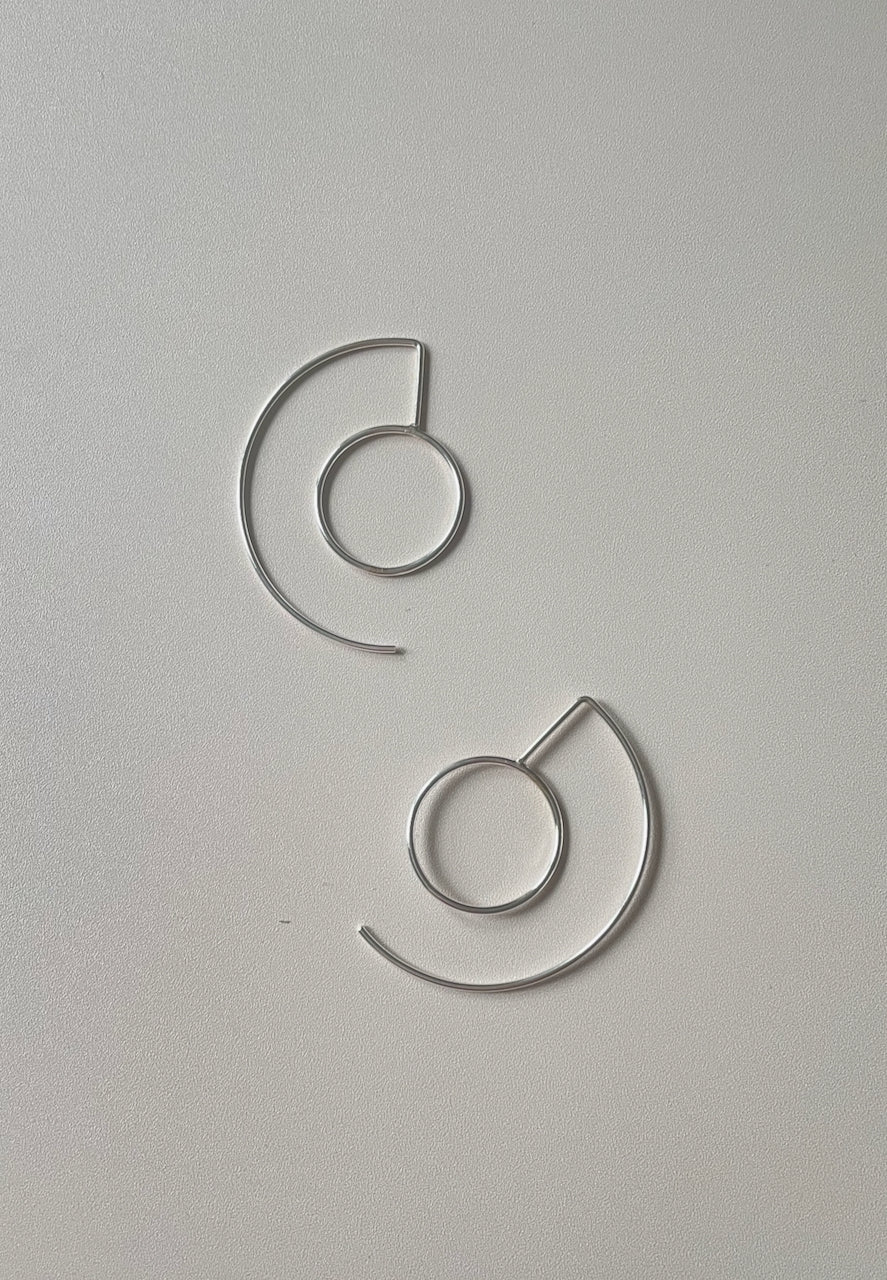A pair of silver hoop earrings on a white background