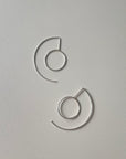 A pair of silver hoop earrings on a white background