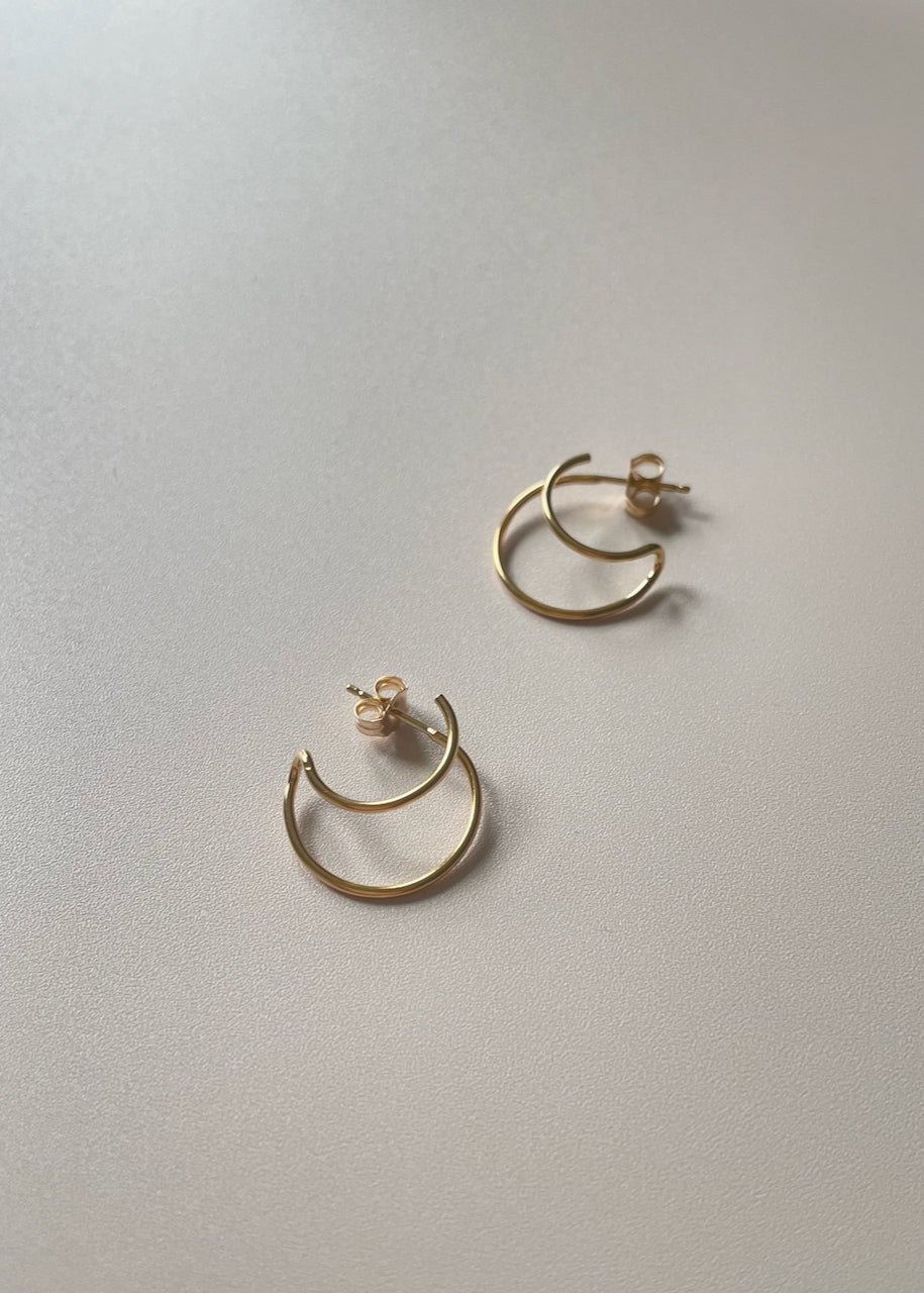 Two Satsuma gold hoop earrings on a light surface. Earrings by Baleen from Seattle, WA