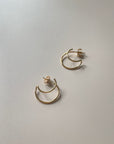 Two Satsuma gold hoop earrings on a light surface. Earrings by Baleen from Seattle, WA