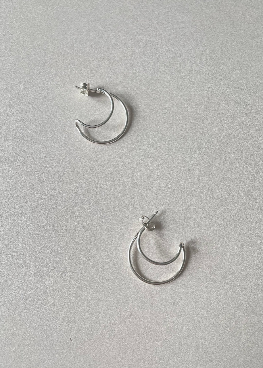 A pair of silver hoop earrings on a white background