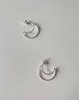 A pair of silver hoop earrings on a white background