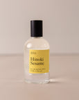 Bottle of perfume by dilo, with a yellow label on the front stating "hinoki sesame. eau de parfum, 50 ml. made in the usa"