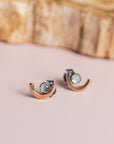 Pair of crescent moon earrings by Claire Sommers Buck on soft pink background