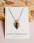 Necklace by 'Claire Sommers Buck' against a natural wood background