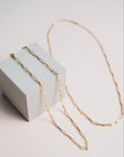Gold link chain necklaces by Gwen Beloti layered over concrete block display