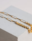 Gold two chain bracelet by gwen beloti on a light gray cube