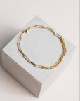 Gold two chain bracelet on a concrete block with pale background