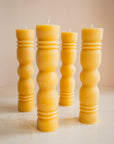 Group of sculpted beeswax candles on a neutral background