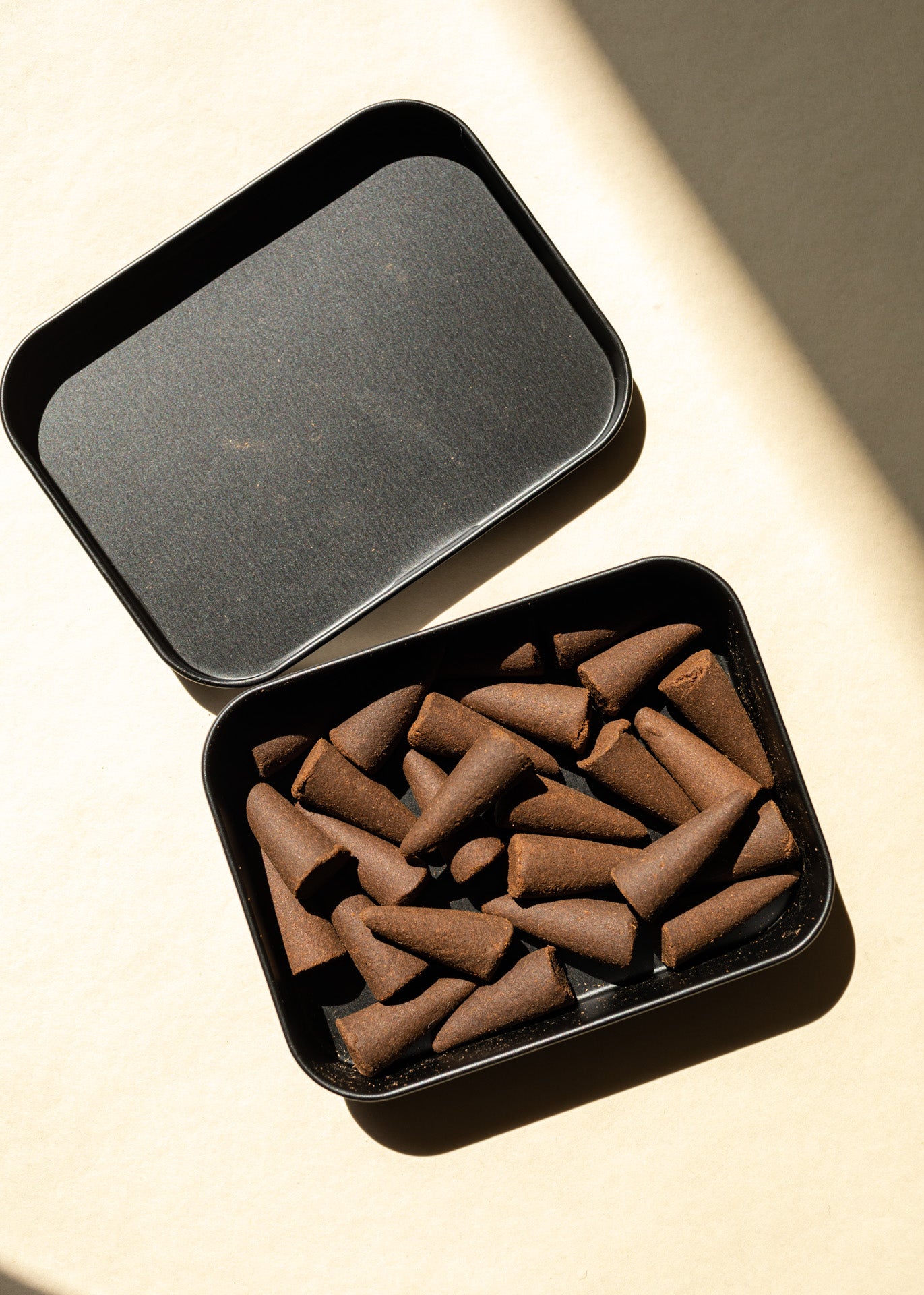 open case with a bunch of brown toned incense inside, on a yellow background