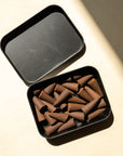 open case with a bunch of brown toned incense inside, on a yellow background