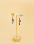 Two Claire Sommers Buck earrings on an earring stand