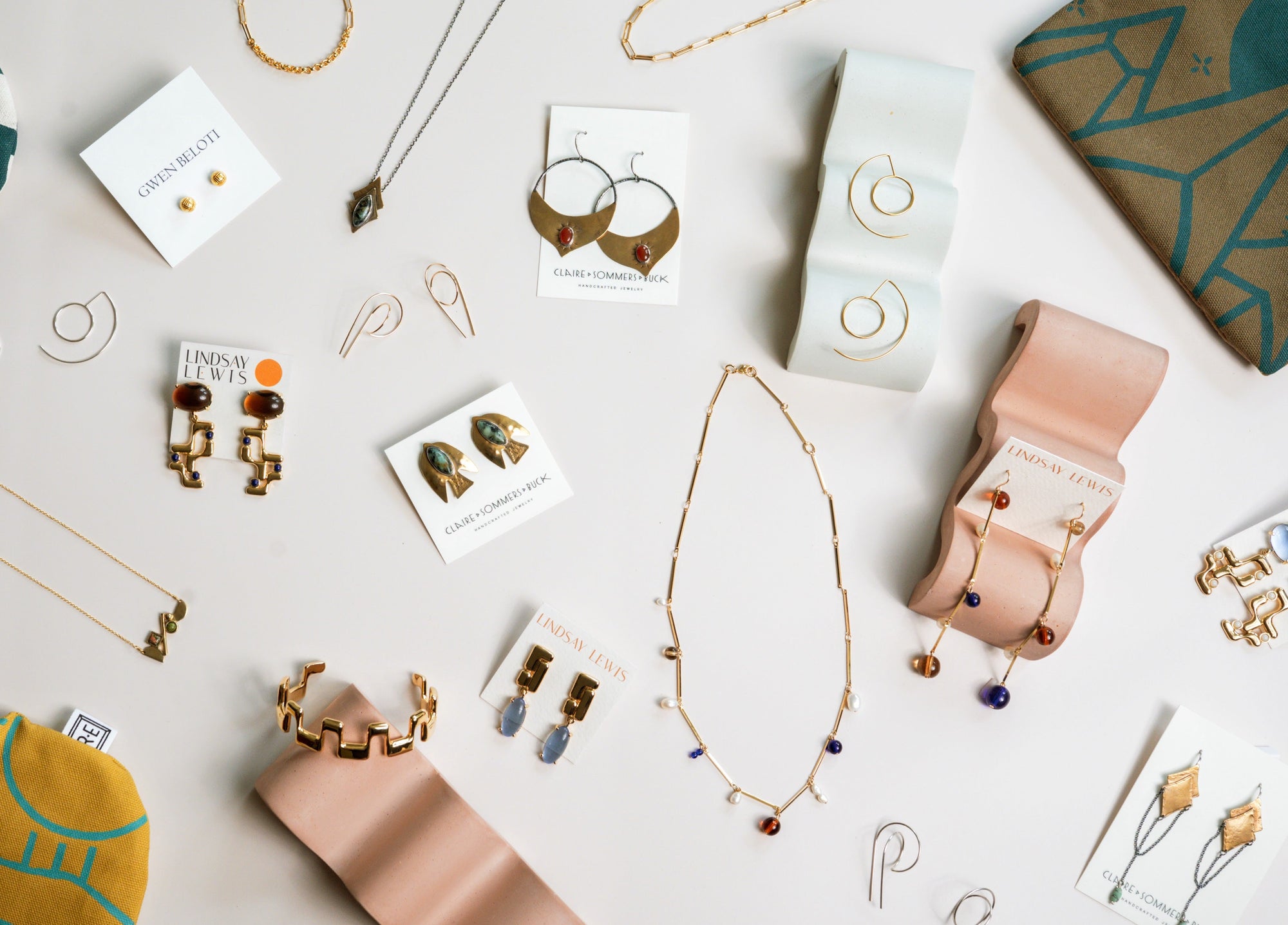 flatlay of a variety of indie jewelry pieces from all over the usa, such as southwest themed necklaces, modern earrings and aztec rings.