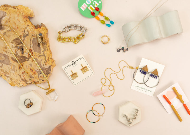 flatlay of a variety of indie jewelry pieces from all over the usa, such as southwest themed necklaces, modern earrings and aztec rings.