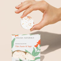 Box of Palo Santo And Sage Shower Steamers With Model Holding One Above