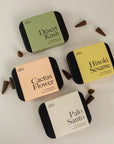 4 boxes of incense cones with incense spread around, all lying on a cream background.