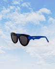 Black sunglasses with a blue temple standing up with a blue sky background
