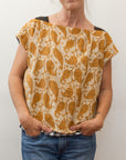 photo of a woman wearing a black and white block print shirt, reversed with a mustard leaf/branch print showing