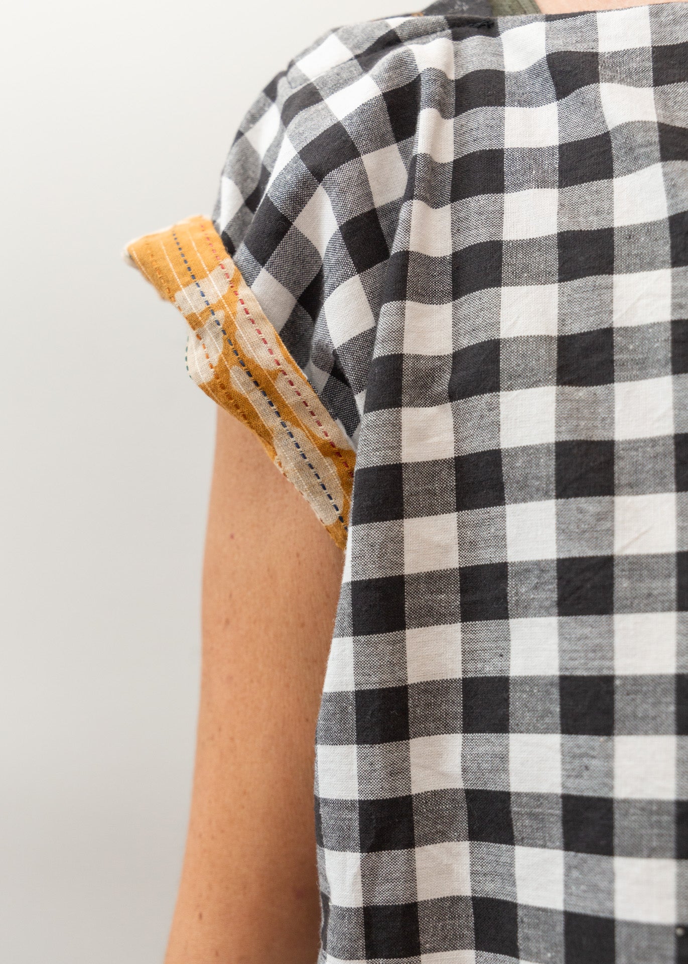 close-up on the sleeve of a woman wearing a black and white block print shirt, with the sleeve slowing a mustard yellow print