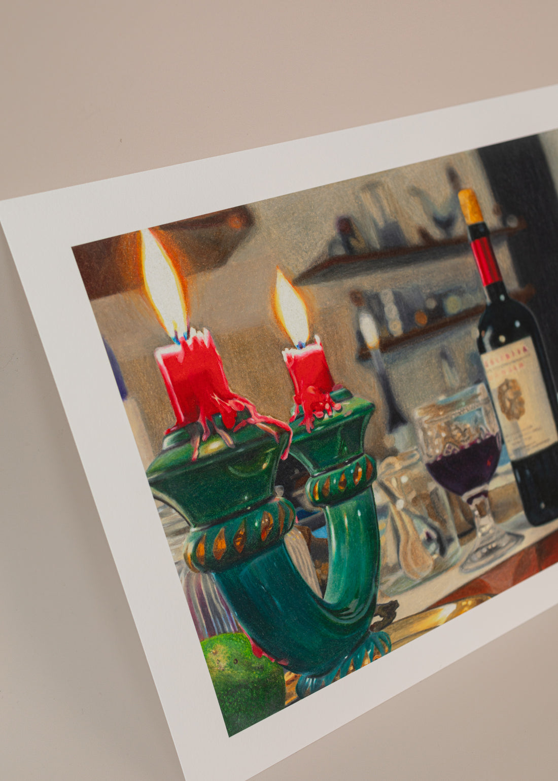 Photo of an art print for an italian series of a bottle of wine with a candle holder in the foreground. Print is in front of a light pink background