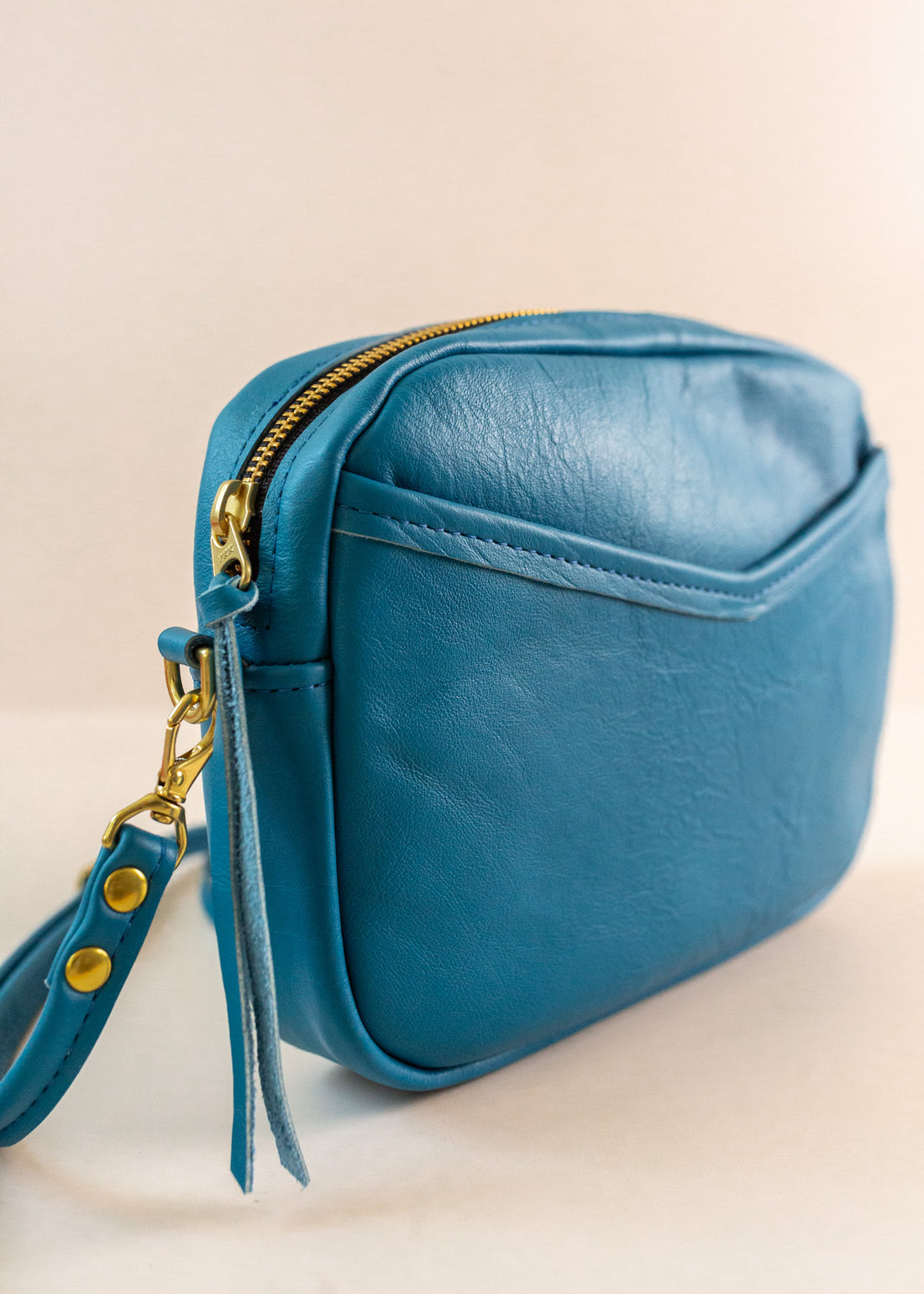 Close-up of cubist handbag in azure, with a v-shaped front pocket and a long thin shoulder strap