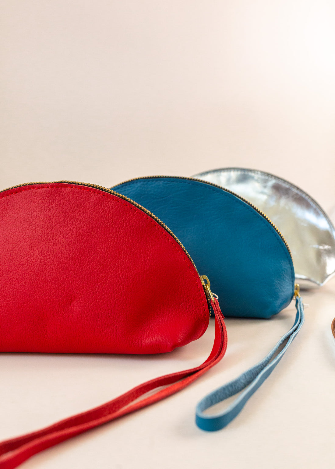 Three shell bags layered from front to back in red, blue and silver