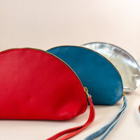 Three shell bags layered from front to back in red, blue and silver