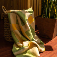 Lime green, cream and mustard blanket falling out of a basket