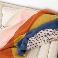 Mutlcolored blanket laid out on a white couch
