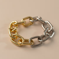 Photo of link bracelet, half silver half gold on a peach background